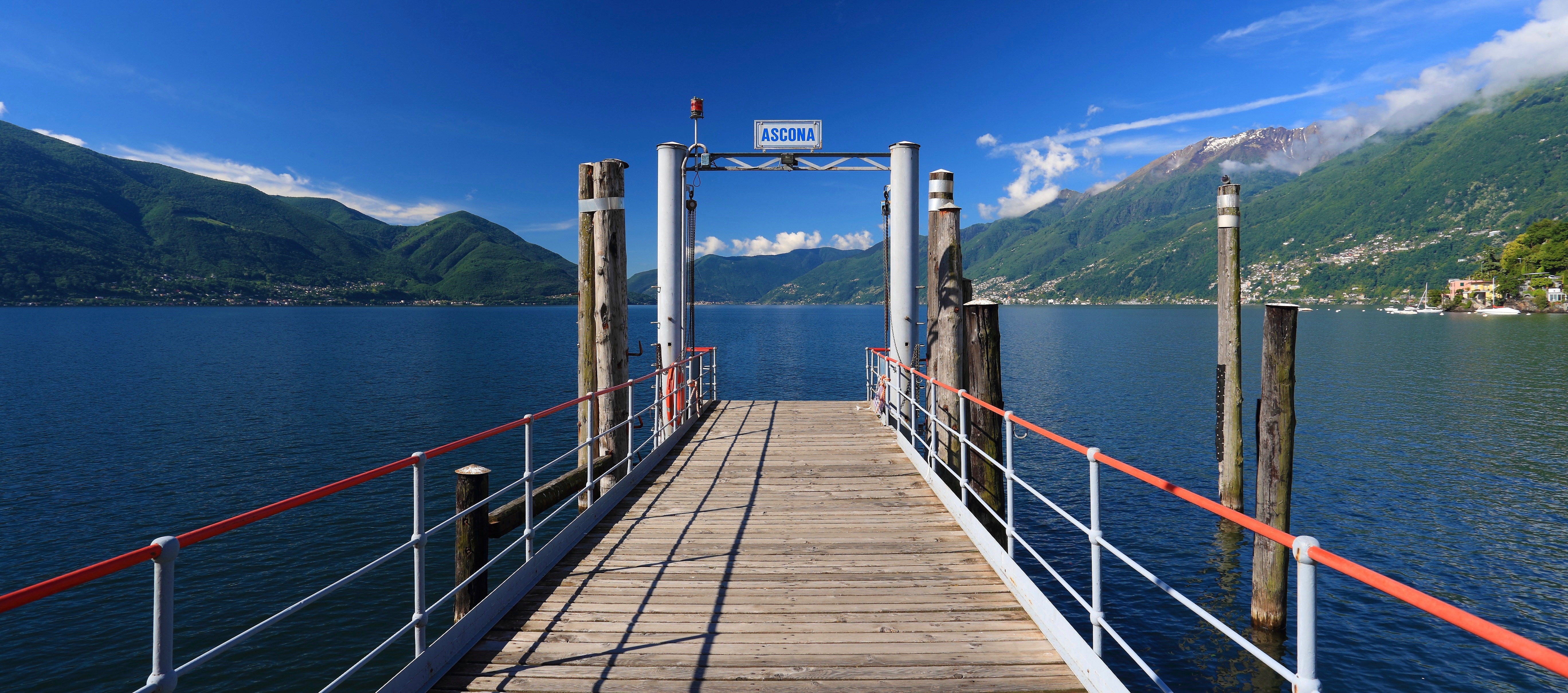 Wooden pier at Ascona extending into a lake with surrounding mountains